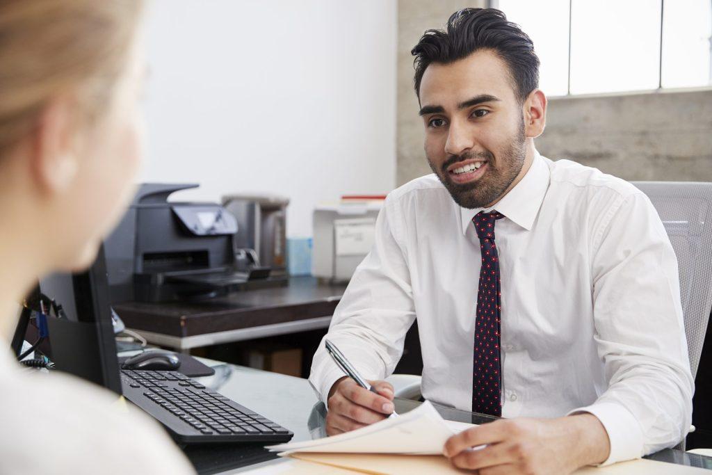 Financial advisor helping customer review loan documents in a local credit union office setting